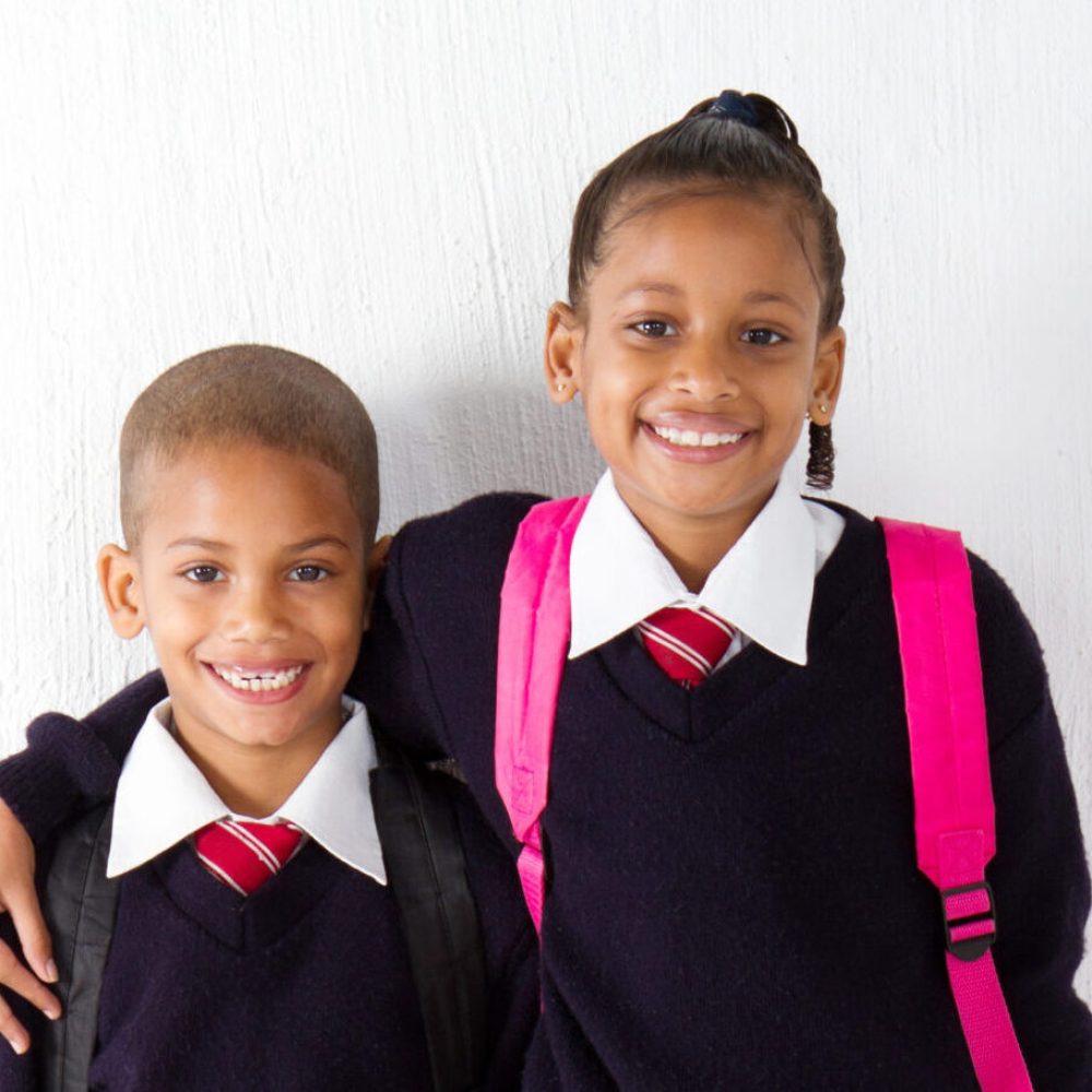 two primary pupils standing against classroom wall